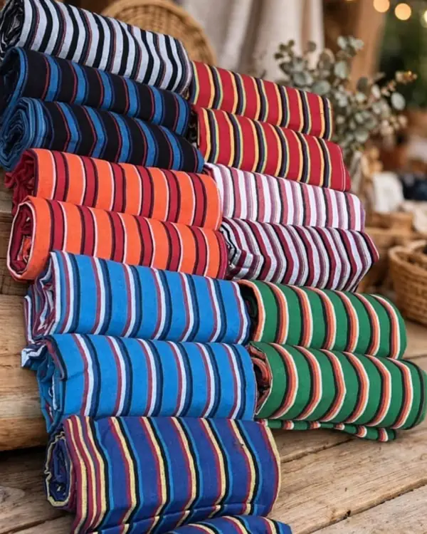 Hamacas trenzadas de colores enrolladas sobre una mesa de madera en la fábrica